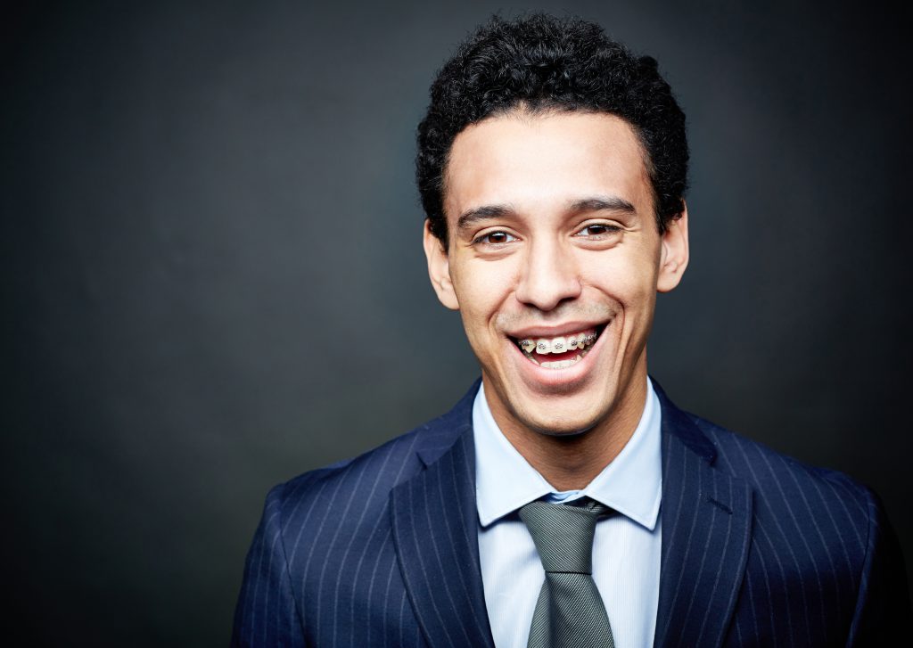 young man in a suit smiling with braces