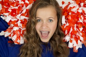 Excited cute teenage cheerleader smiling and wearing braces