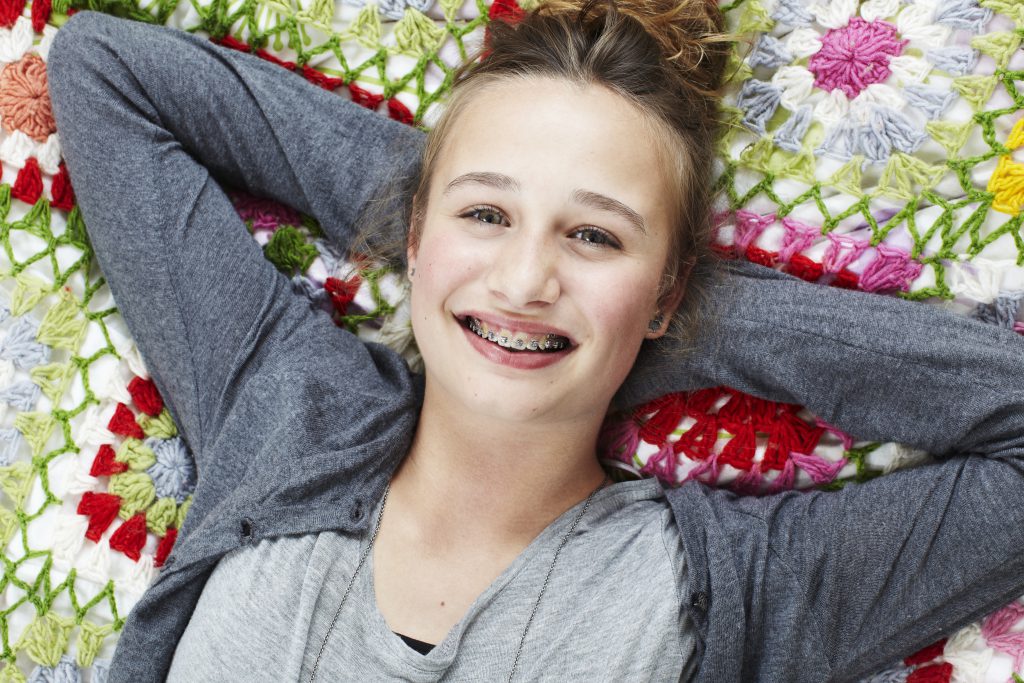 Smiling teenage girl with braces lying on a blanket
