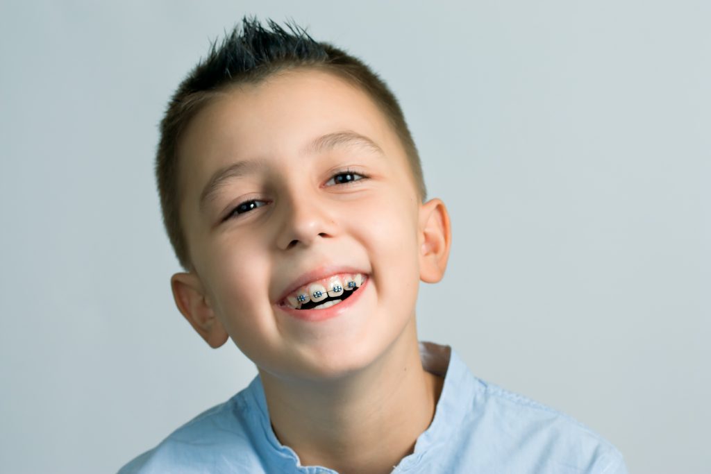laughing boy with braces in front of light blue background