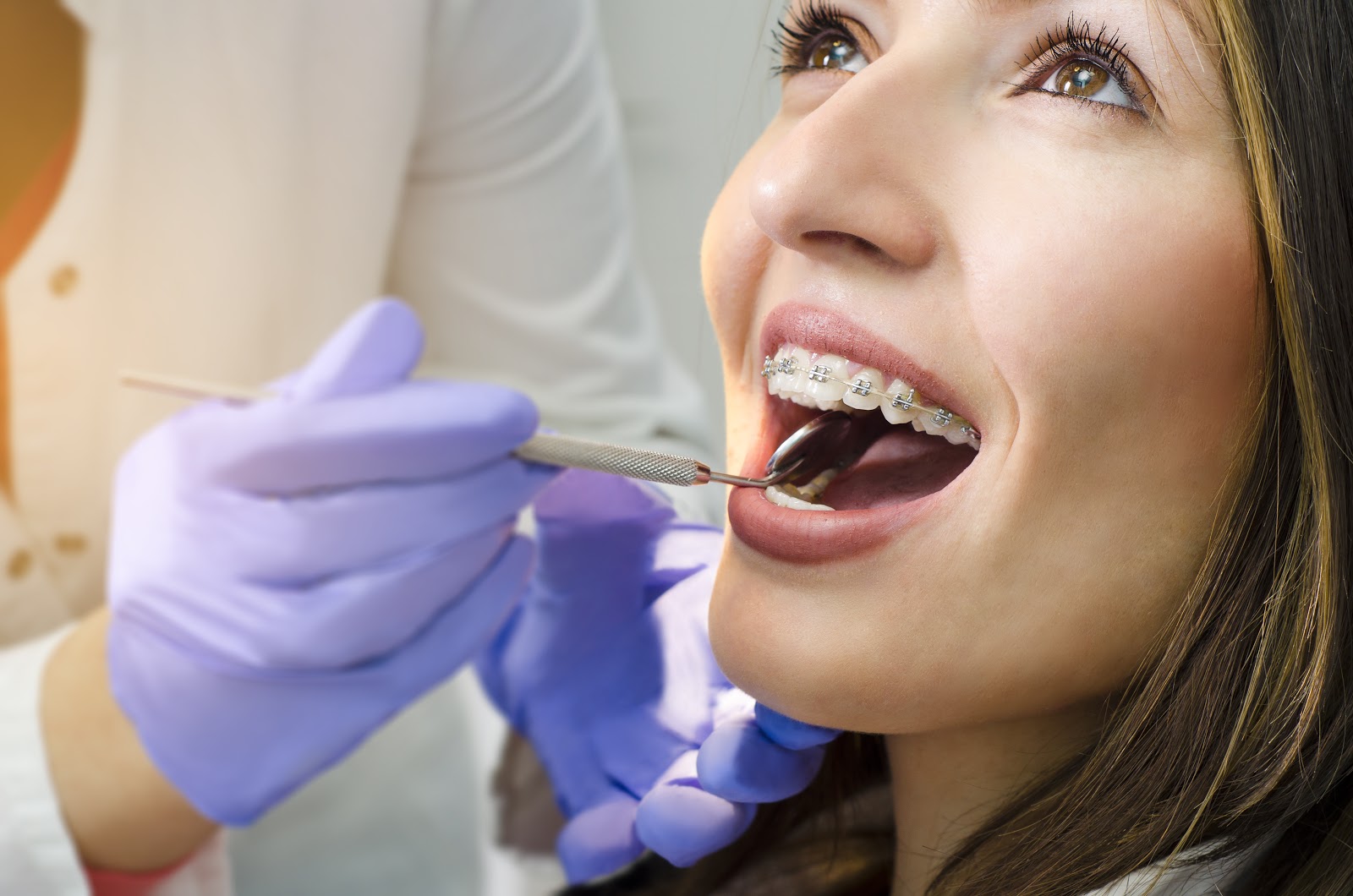 smiling patient with braces receiving a dental exam 