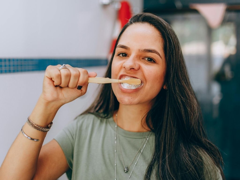 Woman brushing her teeth to maintain healthy oral hygiene while using the best toothpaste for braces.